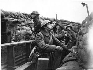 Image shows a staged photo of soldiers demonstrating how to use a periscope and trench mirror to view non mans land