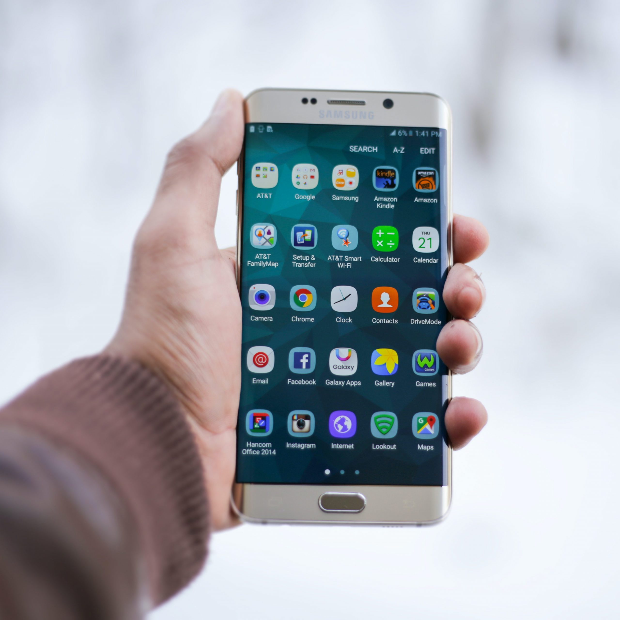 Person Holding Silver Android Smartphone with apps displayed on the screen
